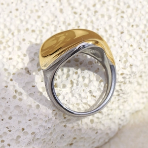 Détail macro d'une bague torsadée bicolore plaquée or 18 carats sur fond de pierre blanche