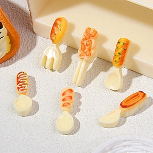 Macro shot of 6 miniature resin food charms featuring bread and hot dogs on tiny cutlery