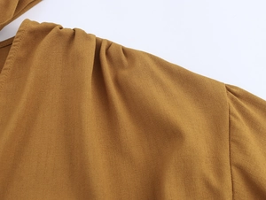Detail of ochre long sleeve top showing shoulder pleats and crepe chiffon texture