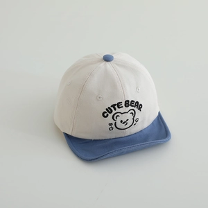 Detail of embroidered Cute Bear logo and blue brim on beige baby baseball cap