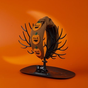 Brown fabric Halloween headband with three beaded pumpkin decorations on a display stand