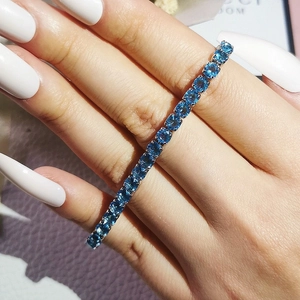 Macro shot of a sparkling blue zircon tennis bracelet with silver prong setting