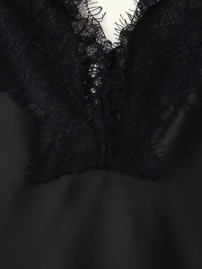 Detailaufnahme eines schwarzen Satin-Kleides mit Wimpernspitze und feinen Nähten
