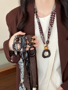 Detail of ethnic fabric scarf necklaces with wooden geometric heart pendants for women