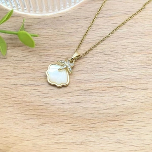 Elegant gold necklace with white shell pendant and diamond-encrusted starfish detail