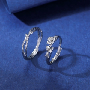 Anelli di coppia regolabili in argento con design a fiori e rami su sfondo blu elegante
