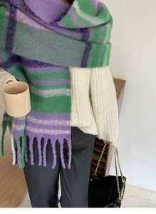 Detail of soft purple and green rainbow plaid scarf with fringe tassels on a model