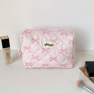 Close-up of pink quilted fabric makeup bag with cute bow patterns and zipper closure
