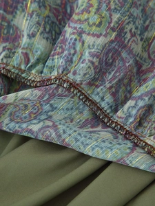Macro shot of paisley chiffon fabric with metallic gold thread and olive green lining