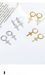 Detail of cross earrings with zircon inlay in gold and silver finish on book pages