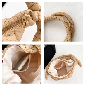 Detail view of beige quilted puff handbag showing metal zipper and interior pocket layout
