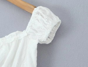 Detail of white eyelet embroidery on puff sleeves and elastic cuffs of a summer dress