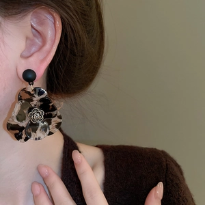 Macro detail of retro leopard print resin flower C-shape earring worn by model