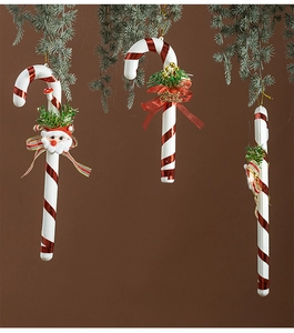 Detail of red and white candy cane ornament with Santa, bow, and pine on tree