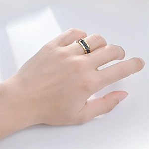 Polished gold stainless steel ring with a textured black frosted band on a model hand