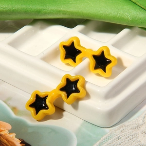 Star-shaped doll sunglasses with yellow resin frames and black lenses on white tray