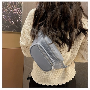 Détail d'un sac bandoulière en cuir PU gris porté avec des fermetures éclair argent