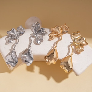 Textured metal flower drop earrings in gold and silver finish shown on white display