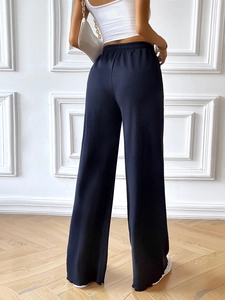 Rear view detail of loose navy blue wide-leg trousers with draped fabric and elastic waist