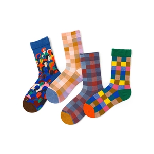 Flat lay of four colorful crew socks with plaid and character patterns on white background