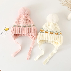 Winter knit baby earflap hats with heart patterns and fluffy pompoms in pink and white