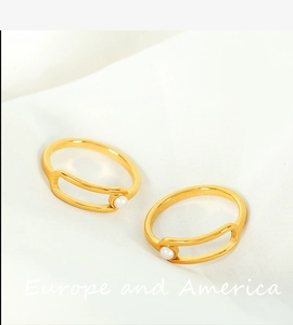 Close-up of two gold-plated titanium steel rings with white pearls on soft fabric