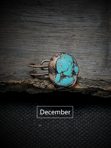 Macro shot of a copper ring with an irregular turquoise stone on tree bark for December