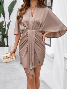 Detail of elegant beige satin dress with V-neck and ruched waist asymmetry