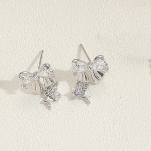 Detailed shot of silver bow earrings with star pendants and clear cubic zirconia stones