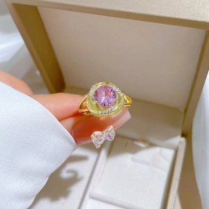 Macro shot of gold ring featuring a large round pink stone and zircon accents