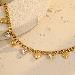 Detailed macro view of gold heart charms and sparkling crystals on stainless steel chain