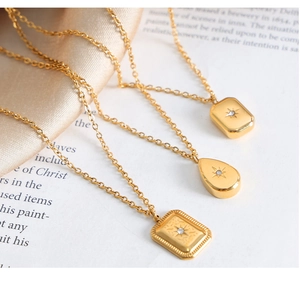Detail of three vintage gold starburst pendant necklaces with cubic zirconia on silk cloth