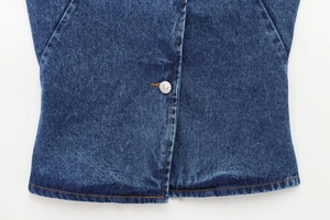 Dettaglio dell'orlo del gilet in denim indaco con bottoni metallici e cuciture arancioni