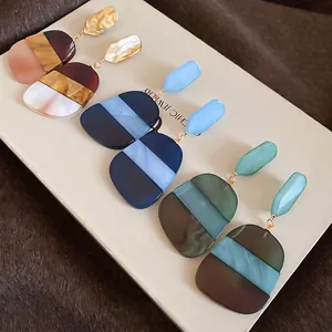 Three pairs of geometric acetate drop earrings with marble patterns on a display card