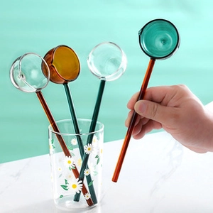 Detail of colorful long-handled glass spoons in amber and green for storage jars