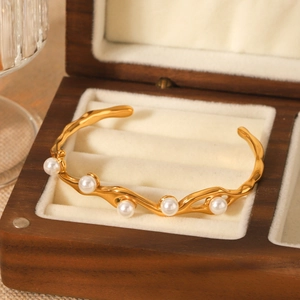 Elegante bracciale rigido a onde placcato oro con perle su fodera di velluto