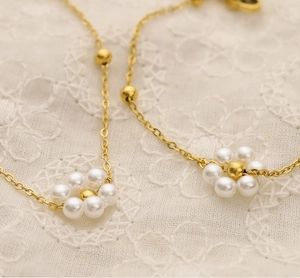 Macro shot of gold necklace with white pearl flower charms on a delicate white lace fabric