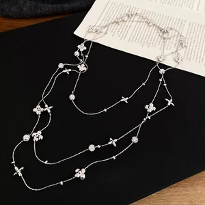 Elegant multi-layer silver necklace with diamond-set flowers and star pendant on black fabric