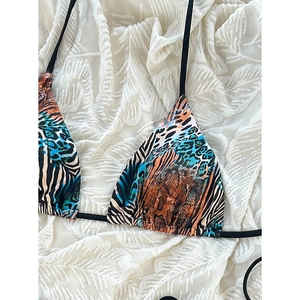 Detail view of bikini top with mixed tiger and leopard animal prints and black tie straps