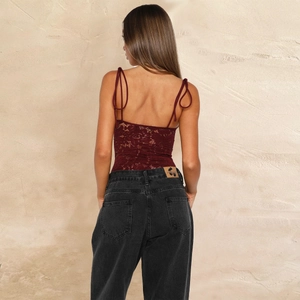 Rear view detail of dark red lace patchwork bodysuit paired with black high-waist jeans