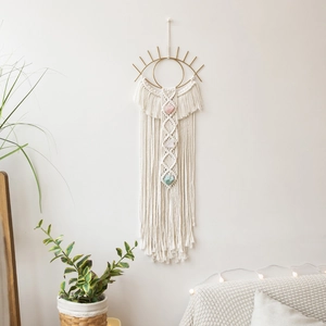 Detailed shot of handmade macrame evil eye wall hanging with natural crystals and tassels