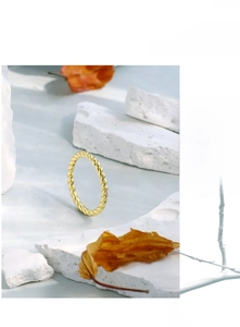 Macro shot of 18K gold plated twisted rope ring on a minimalist stone background