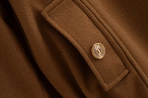 Close-up of brown wool coat featuring a vintage marble-pattern button and thick fabric texture