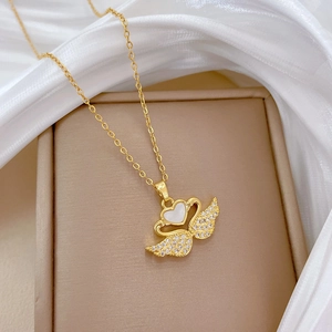Detail of gold swan necklace with sparkling crystals and heart-shaped shell inlay