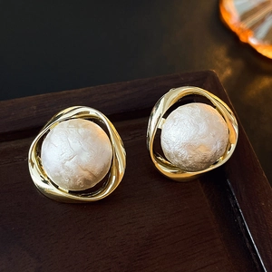 Macro shot of minimalist gold geometric earrings with textured matte white pearls
