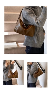 Detail view of large brown leather hobo bag with vertical stitching and smooth matte finish