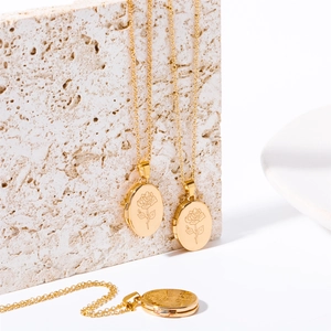 Macro view of oval gold locket necklace featuring a delicate rose engraving detail