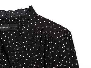 Detail of ruffled stand-up collar and V-neckline on white polka dot chiffon top