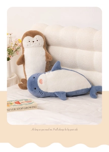 Close-up of soft plush seal and shark pillows resting on a white bed in a cozy room