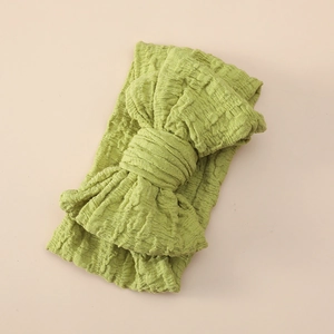 Detail view of grass green waffle fabric baby headband with a large layered bow